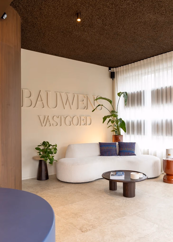 De wachtruimte van Bauwens Vastgoed, met de kantoornaam in reliëf op de muur